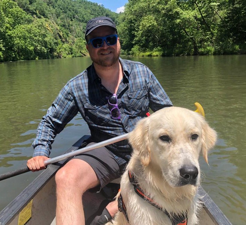 Lalo canoeing on a river with his golden retriever